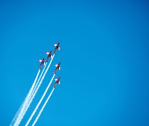 Low angle view of airplanes performing air show in clear blue sky