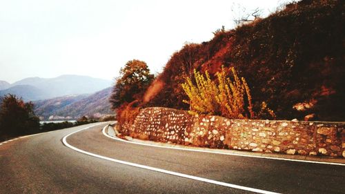 Road by trees against mountain