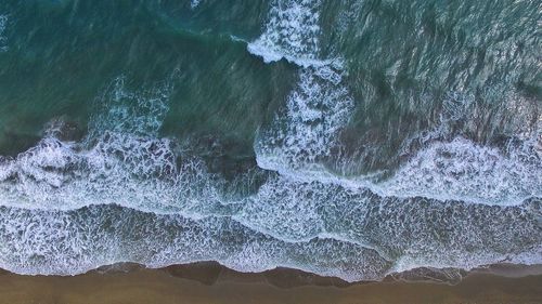 High angle view of sea waves splashing on rocks