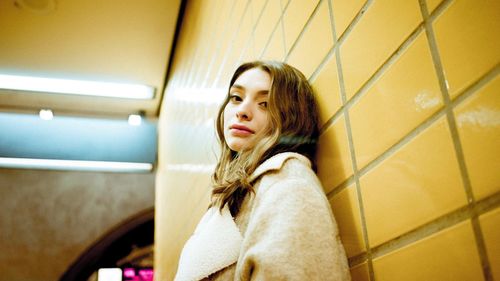 Portrait of young woman leaning on wall