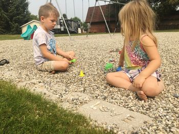 Girl playing with children sitting outdoors