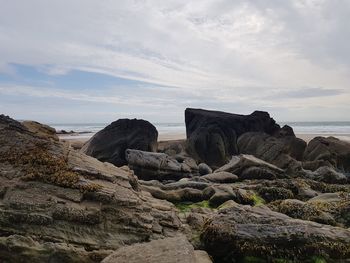 Rocks on shore by sea against sky