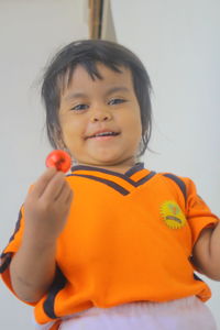 Portrait of cute boy holding orange indoors