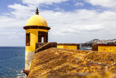 Lighthouse by sea against sky