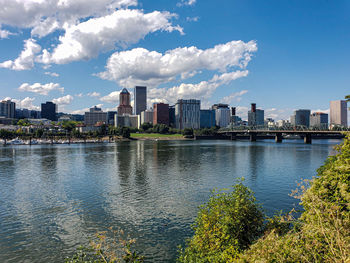 Scenic view of river by buildings against sky