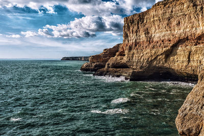 Scenic view of rocks on sea against sky