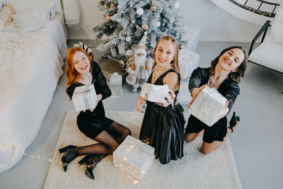 Full length portrait of cheerful female friends standing by christmas tree