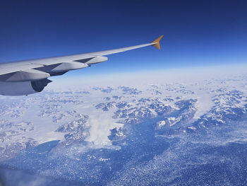 Airplane flying over snowcapped mountain against sky