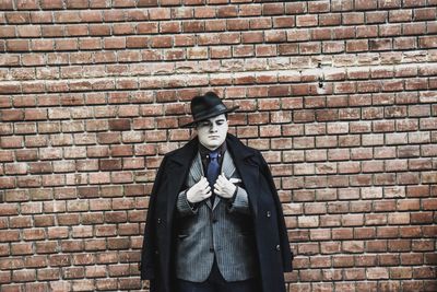 Man standing against brick wall