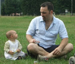 Father with cute daughter sitting on grassy land