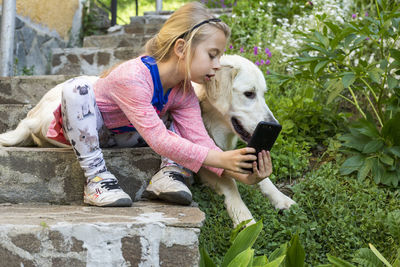 Girl taking selfie from mobile phone with dog on steps