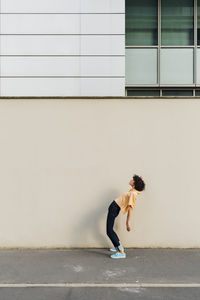 Woman bending backwards in front of wall