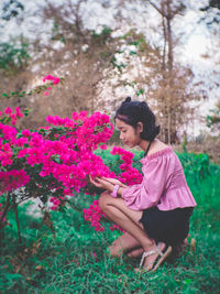 Woman with pink flowers against plants