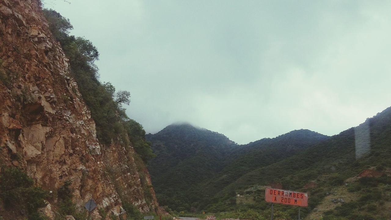 mountain, sky, mountain range, landscape, scenics, tranquil scene, text, tranquility, beauty in nature, nature, cloud - sky, communication, non-urban scene, tree, western script, cloud, day, hill, rock - object, sign