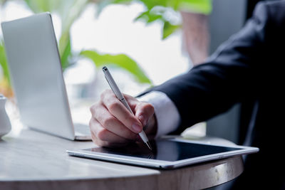 Midsection of man using mobile phone on table