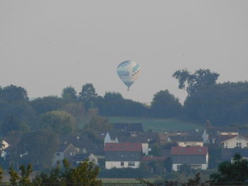 Hot air balloon flying over trees against sky