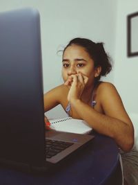 Portrait of teenage girl sitting on table at home