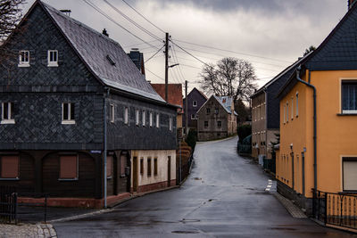 Empty road amidst buildings against sky