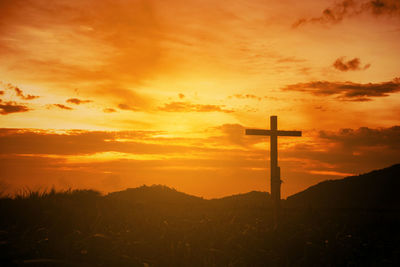 Silhouette cross against sky during sunset