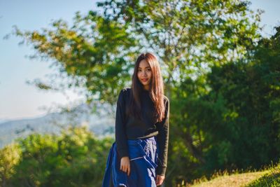 Portrait of smiling young woman against trees