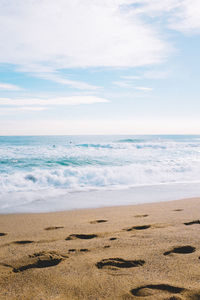 Footprints on beach with sky in background