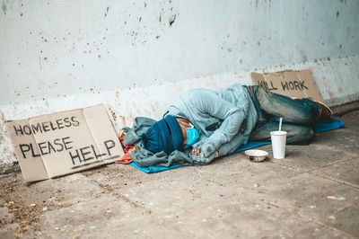 Rear view of man sleeping on street in city