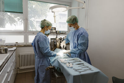 Male and female surgeons performing surgery in operating room at animal hospital