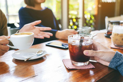 Midsection of woman holding coffee cup on table