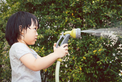 Cute girl watering plants standing at lawn