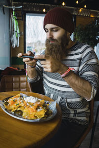 Hipster man photographing food served in plate with smart phone at cafe