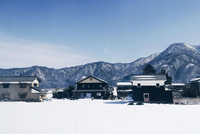 Houses on snowcapped mountain against sky