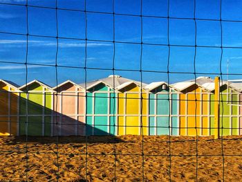 Multi colored swimming pool by building against blue sky