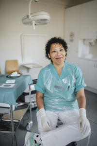 Portrait of smiling female doctor wearing uniform sitting in medical examination room