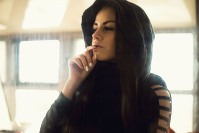 Thoughtful young woman wearing hooded shirt at home