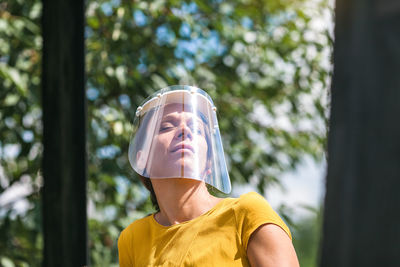 Close-up of woman wearing face shield against trees