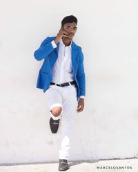 Portrait of young man wearing sunglasses standing against white background