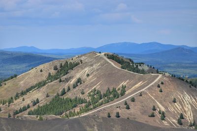 Scenic view of road by mountains against sky