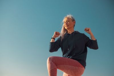 Portrait of young woman standing against clear sky