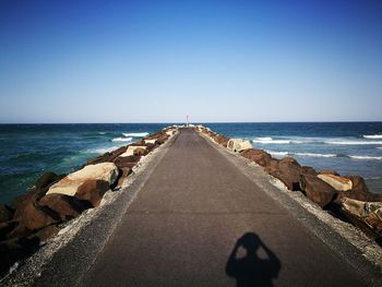 Rear view of woman on beach against clear blue sky