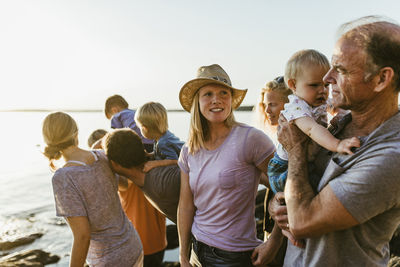 Family with children standing at beach against clear sky during sunset