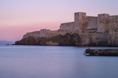 Castle by sea against sky during sunset