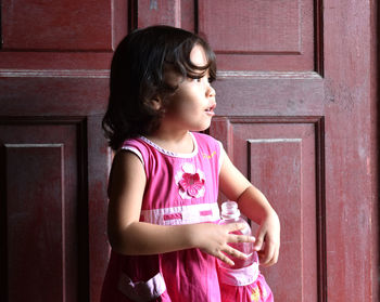 Side view of girl standing against wall