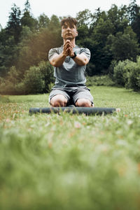 Young man doing exercises outside on grass during his calisthenics workout