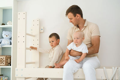 Children are exercising on toddler indoor gym playset. kid climbing the ladder in playroom. siblings