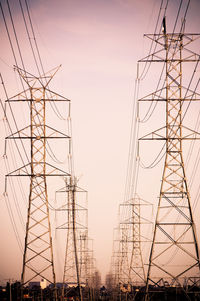 Low angle view of silhouette electricity pylon against sky