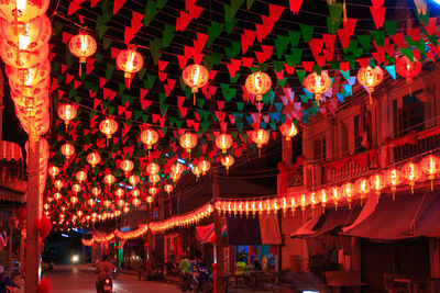 Illuminated lanterns hanging over street at night