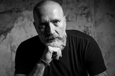 Close-up portrait of serious mature man with beard against wall
