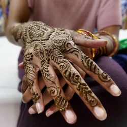 Midsection of woman with henna tattoo on hand