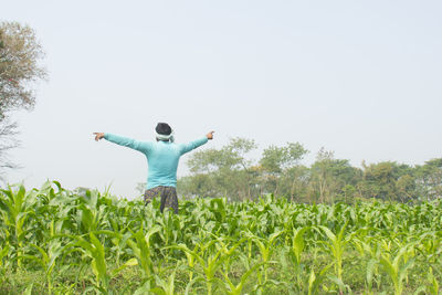 Rear view of man standing on field against sky