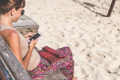 Midsection of woman using mobile phone at beach